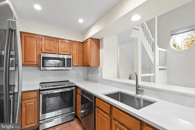 a kitchen with granite countertop a sink dishwasher stove and microwave with wooden cabinets