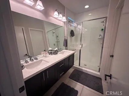 a bathroom with a double vanity sink a large mirror and shower
