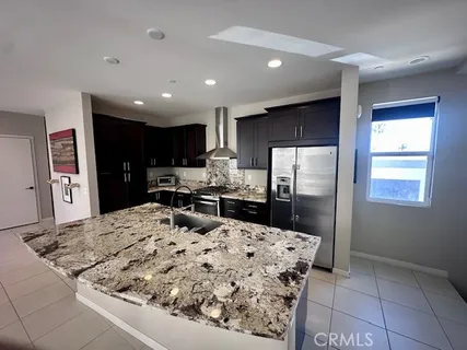 a kitchen with stainless steel appliances kitchen island granite countertop a refrigerator and a stove top oven