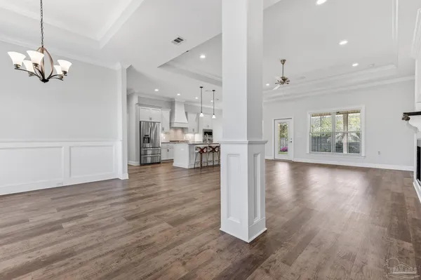 an empty room with wooden floor chandelier and glass door