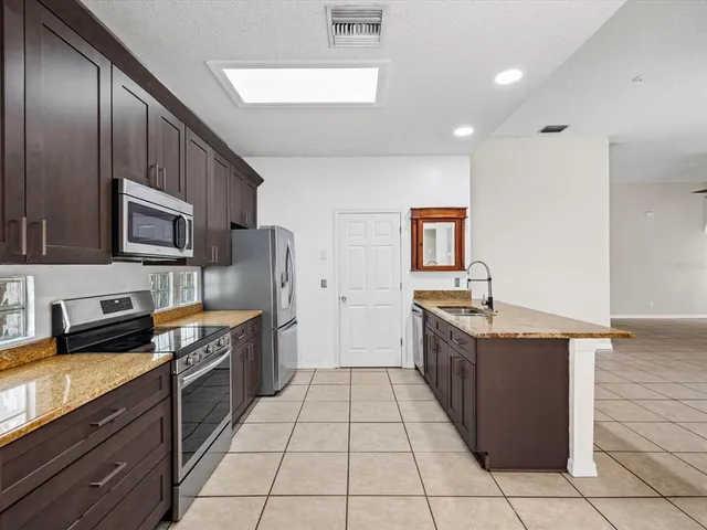 a kitchen with stainless steel appliances granite countertop a stove a sink and a refrigerator