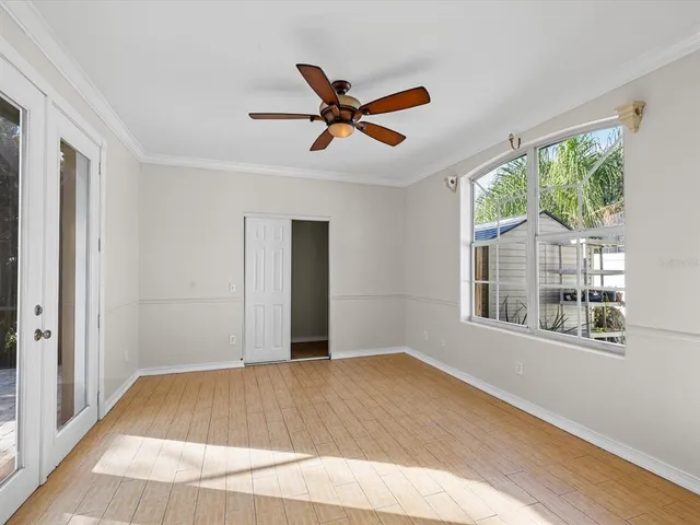 a view of empty room with wooden floor and fan
