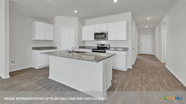 a large white kitchen with cabinets and a wooden floor