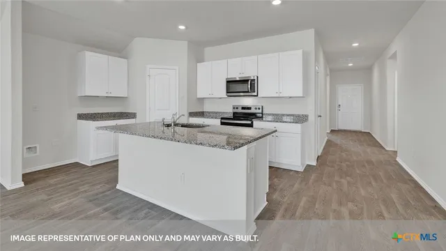 a kitchen with granite countertop a sink and white cabinets