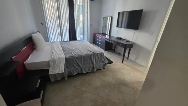 a bedroom with a bed tv and a window