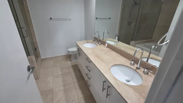 a bathroom with a granite countertop double vanity sink and mirror