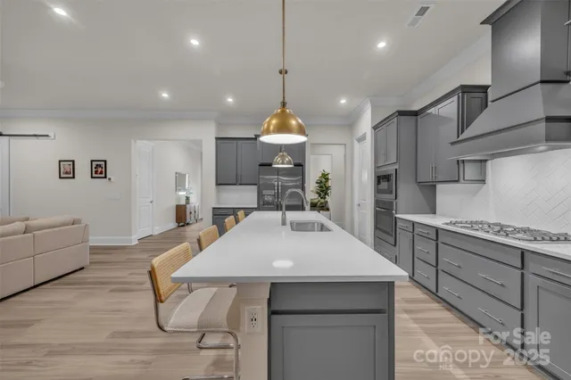 a kitchen with stainless steel appliances granite countertop a kitchen island a stove and a sink