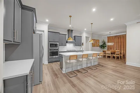 a kitchen with stainless steel appliances a stove top oven a sink dishwasher and a refrigerator with wooden floor