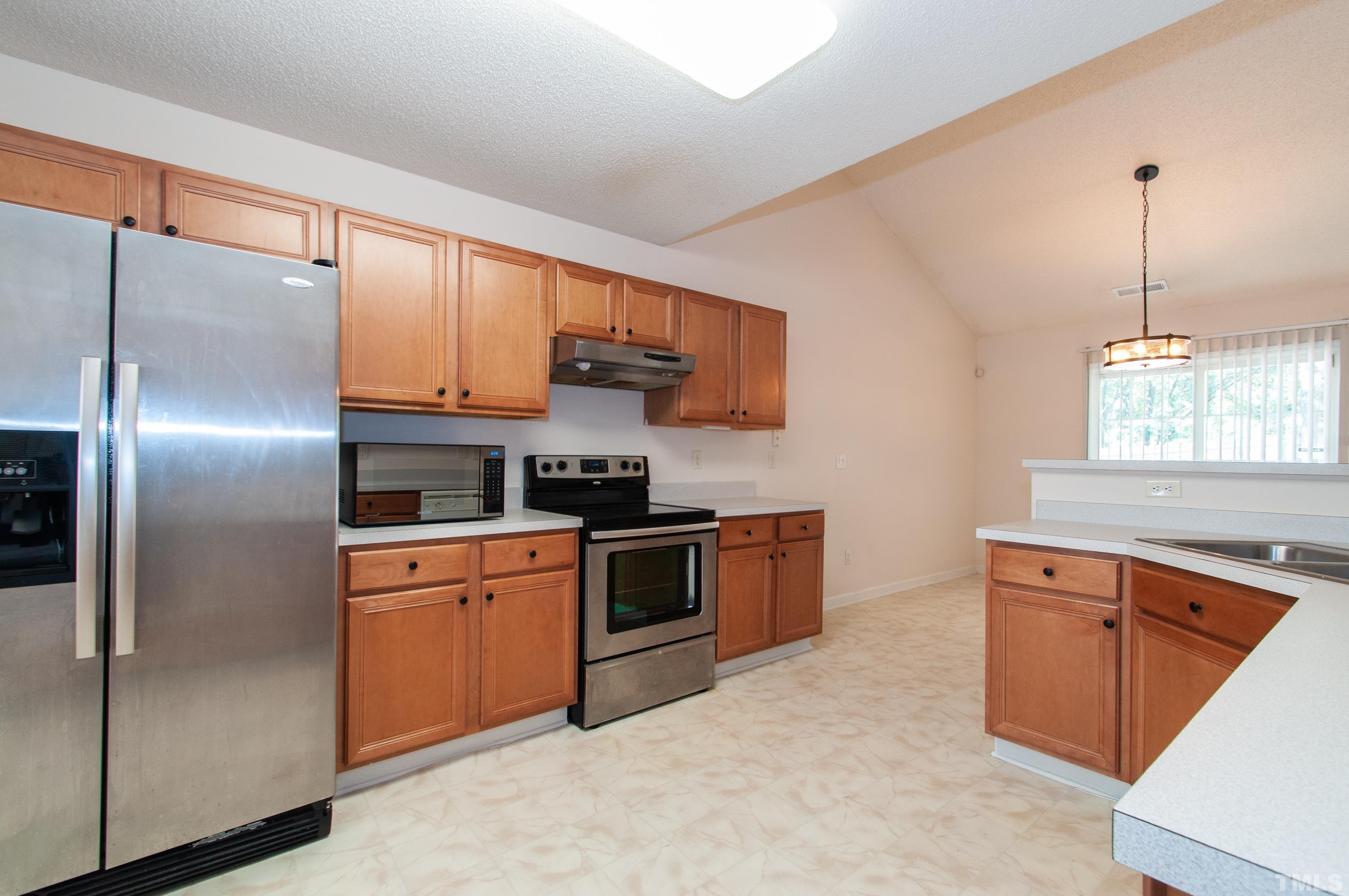 4617 Dresden Village Drive Raleigh, NC 27604 - Photo 11 of 33 a kitchen with stainless steel appliances granite countertop a refrigerator a sink dishwasher a stove with wooden cabinets