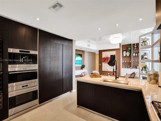a kitchen with stainless steel appliances kitchen island granite countertop a refrigerator and a sink