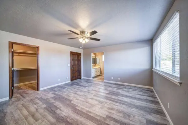 a view of an empty room with window and chandelier fan