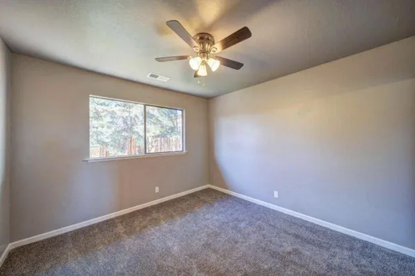 an empty room with a window and a fan
