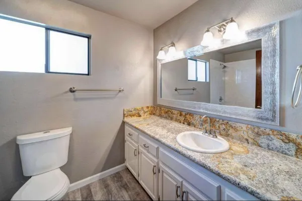 a bathroom with a granite countertop sink toilet and mirror