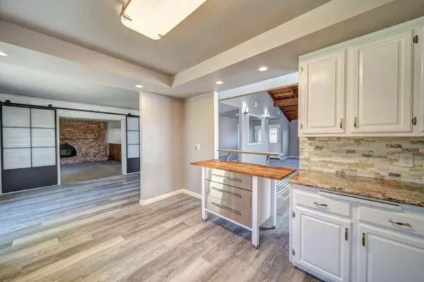 a kitchen with granite countertop a stove and white cabinets