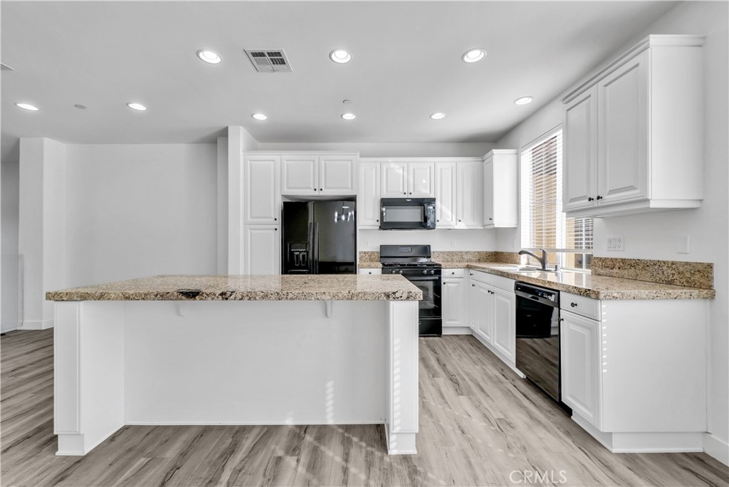 8415 Kendra Loop Orange, CA 92867 - Photo 15 of 36 a kitchen with stainless steel appliances granite countertop a stove top oven a sink dishwasher and a refrigerator with wooden floor