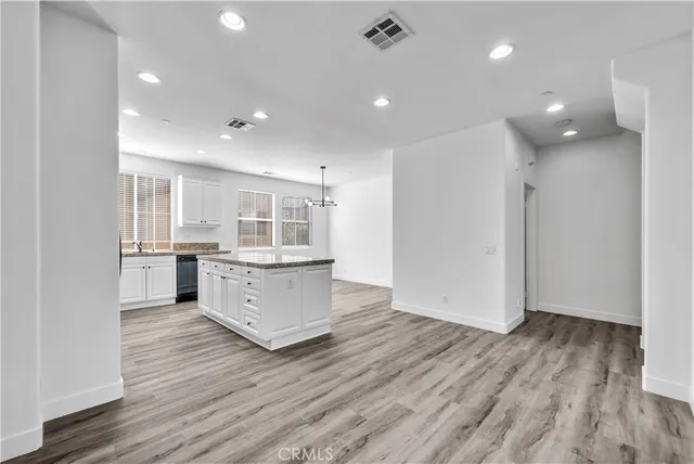 a kitchen with stainless steel appliances granite countertop a stove top oven a sink dishwasher and a refrigerator with wooden floor