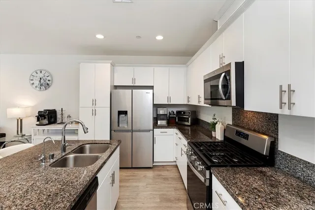 a kitchen with granite countertop kitchen island stainless steel appliances refrigerator sink and stove