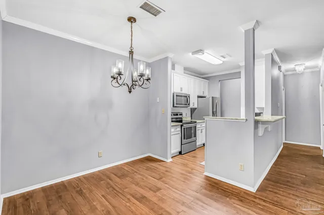 a view of a kitchen with a refrigerator a stove top oven and wooden floor