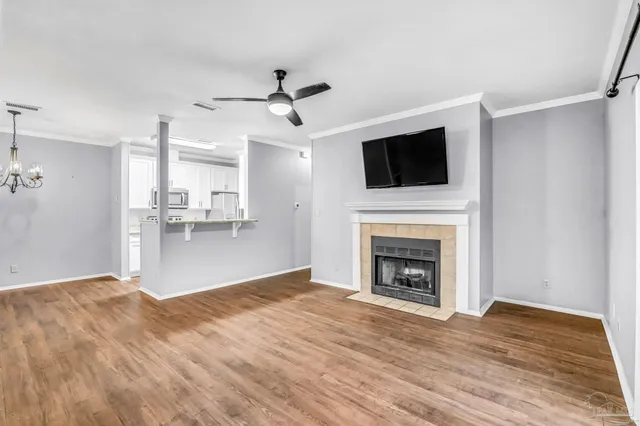 a view of a livingroom with a fireplace a ceiling fan and windows