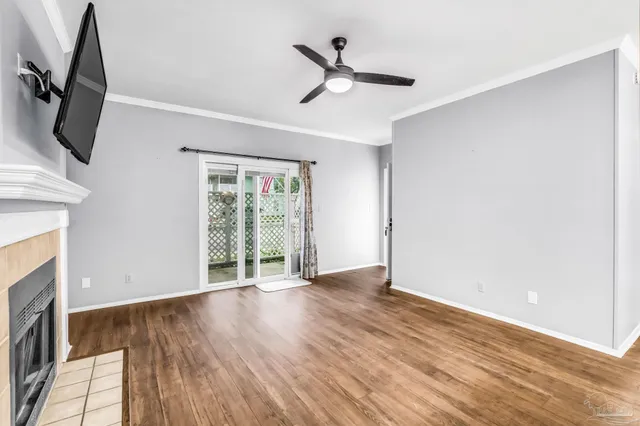 an empty room with wooden floor fan and windows