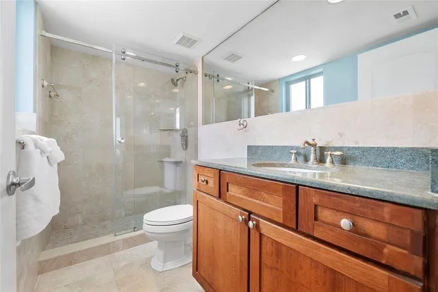a bathroom with a granite countertop sink a toilet and shower