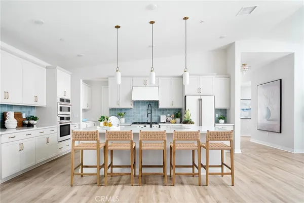 a kitchen with stainless steel appliances kitchen island granite countertop a dining table chairs and white cabinets