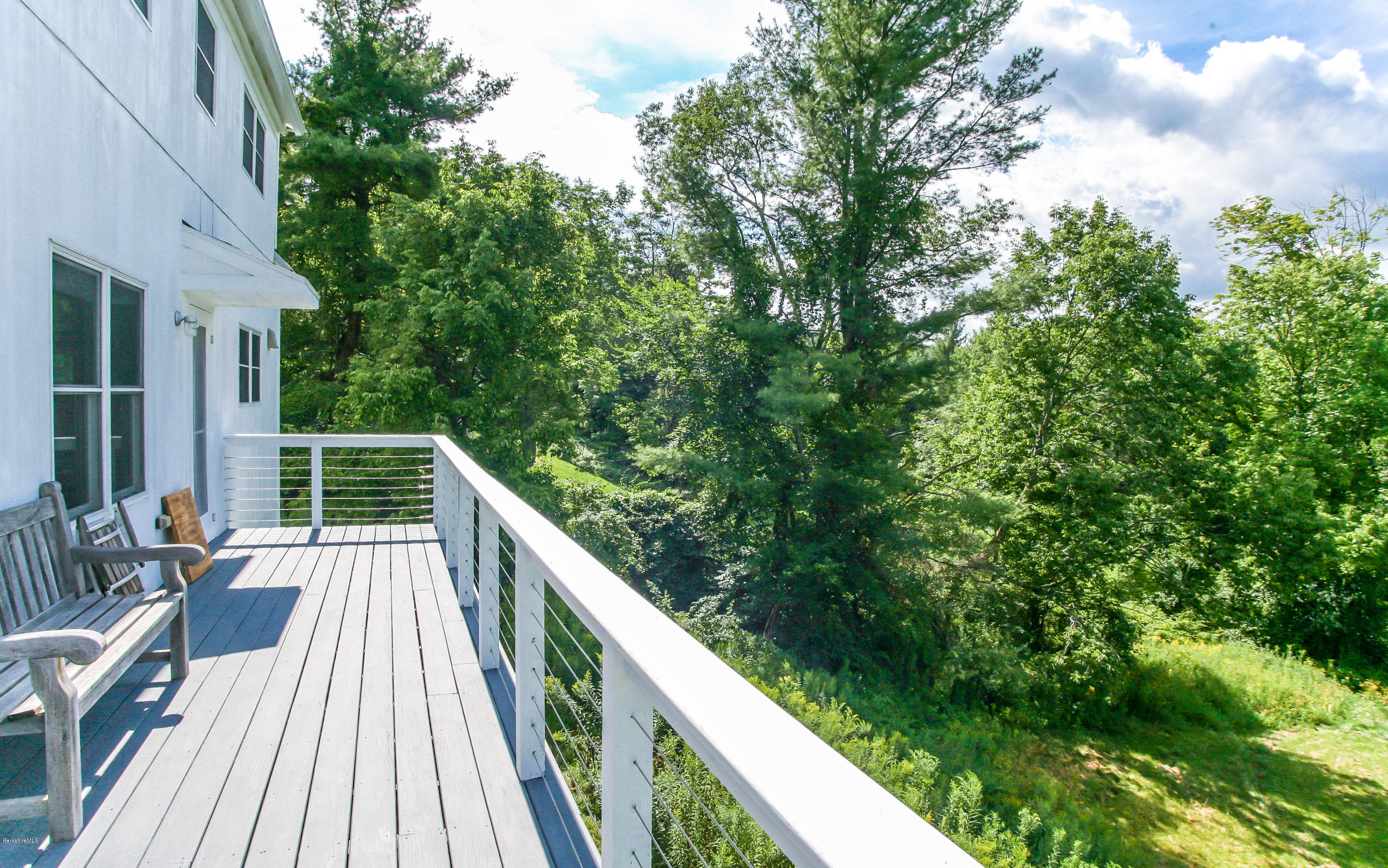 394 Main Road Monterey, MA 01245 - Photo 28 of 33 a balcony with wooden floor and trees in the back