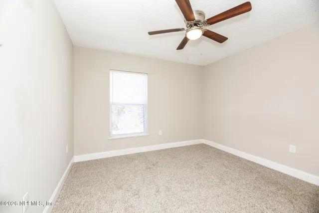 an empty room with a window and a fan