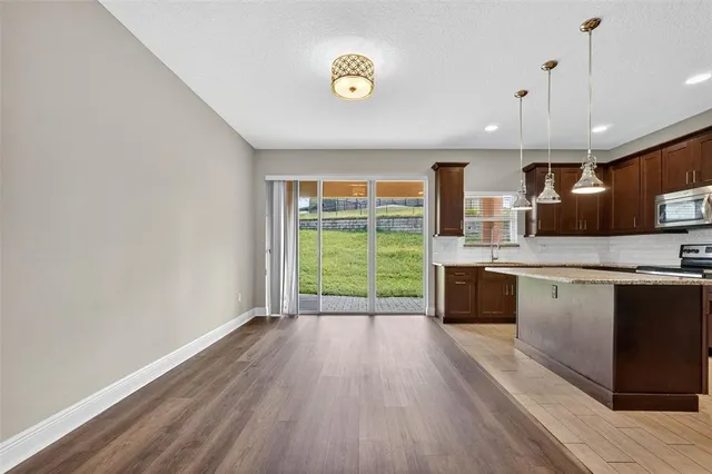 a kitchen with stainless steel appliances granite countertop a refrigerator a stove and a sink with wooden floor