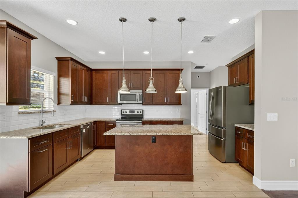 280 Wallrock Drive Ocoee, FL 34761 - Photo 16 of 88 a large kitchen with stainless steel appliances kitchen island granite countertop a large counter top stainless steel appliances and cabinets