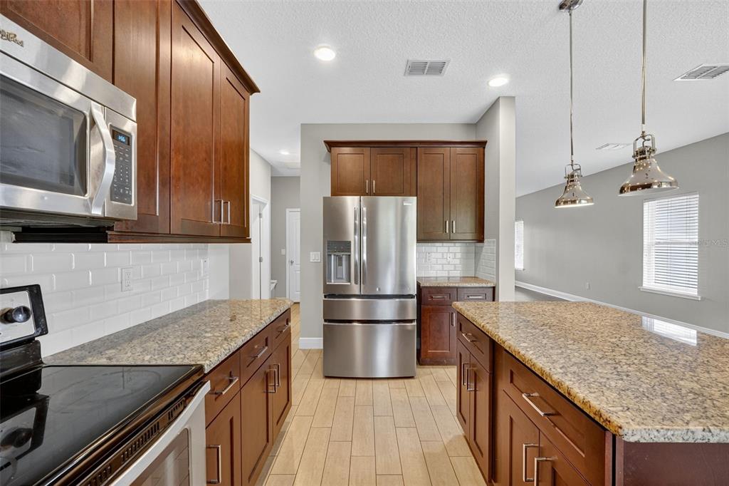 280 Wallrock Drive Ocoee, FL 34761 - Photo 20 of 88 a kitchen with stainless steel appliances granite countertop a refrigerator a stove and a sink with wooden floor