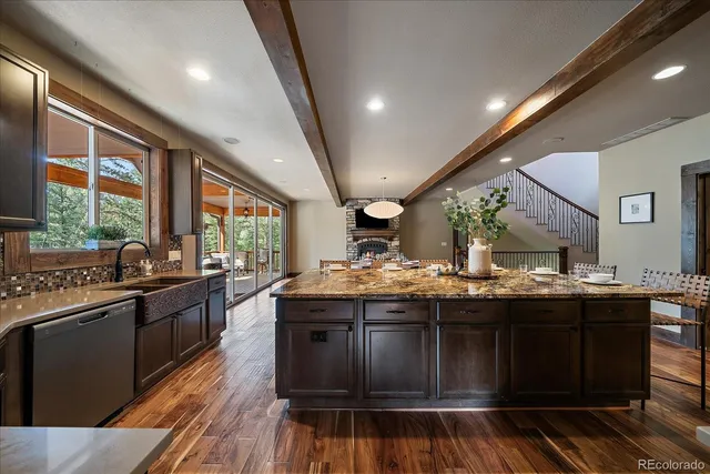 a kitchen with stainless steel appliances granite countertop a stove top oven a sink dishwasher a dining table and chairs with wooden floor