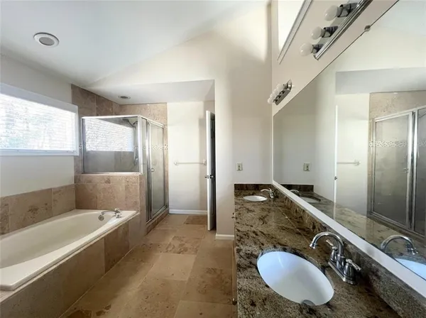 a bathroom with a granite countertop tub sink and mirror