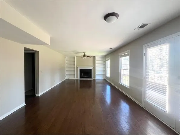 a view of empty room with wooden floor and fireplace
