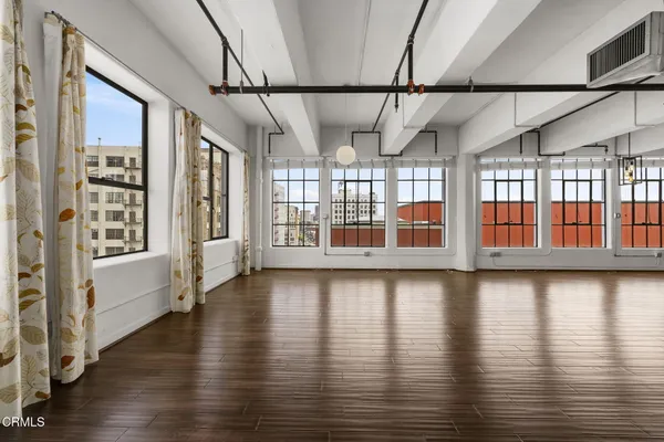 a view of an empty room with wooden floor and windows