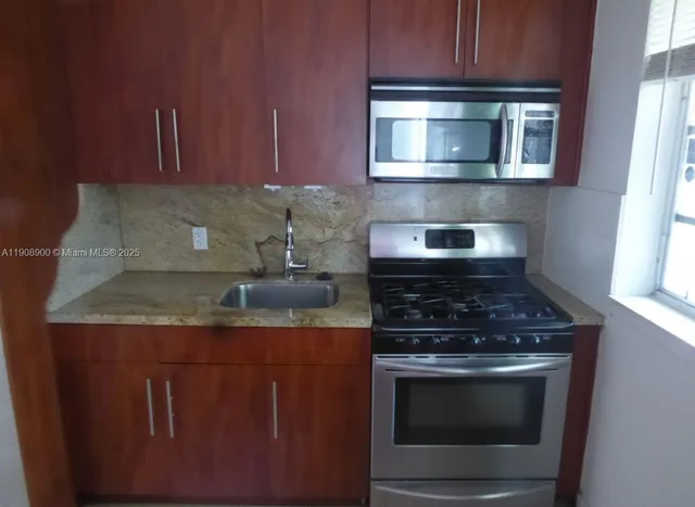 a kitchen with granite countertop a stove top oven microwave and cabinets