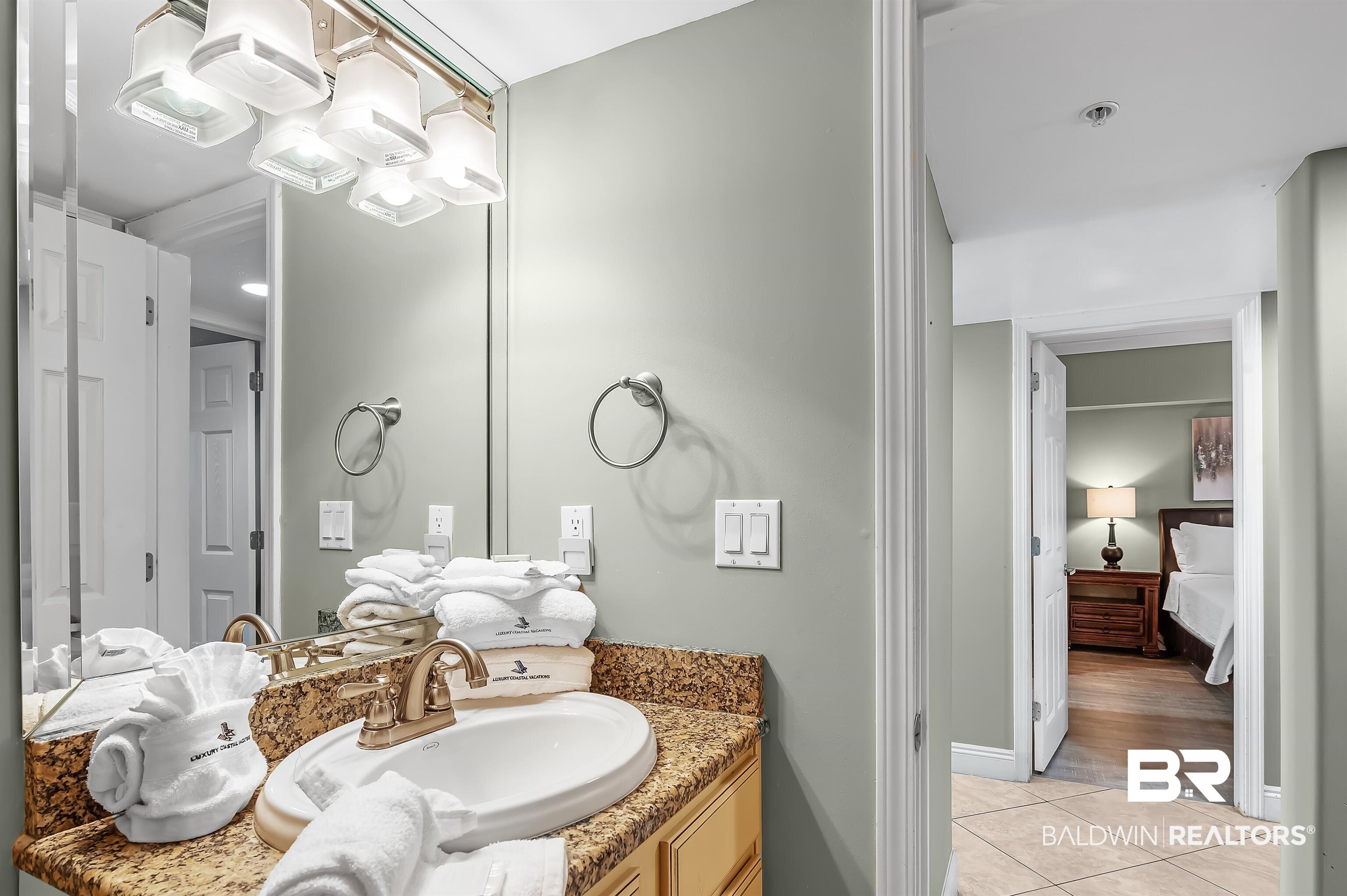 16287 Perdido Key Drive, Unit 105 Pensacola, FL 32507 - Photo 34 of 66 Bathroom vanity featuring an oval undermount sink with a bronze-finish faucet, a speckled countertop, and a large wall mirror