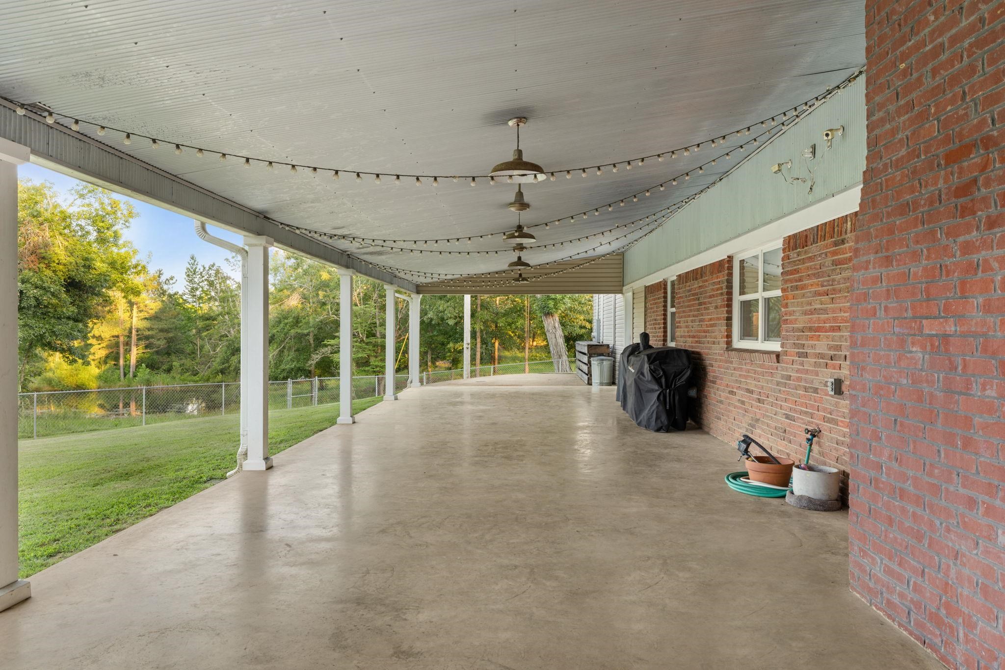 66 County Road 511 Corinth, MS 38834 - Photo 29 of 40 Expansive covered patio with concrete flooring, brick exterior wall, and multiple support columns