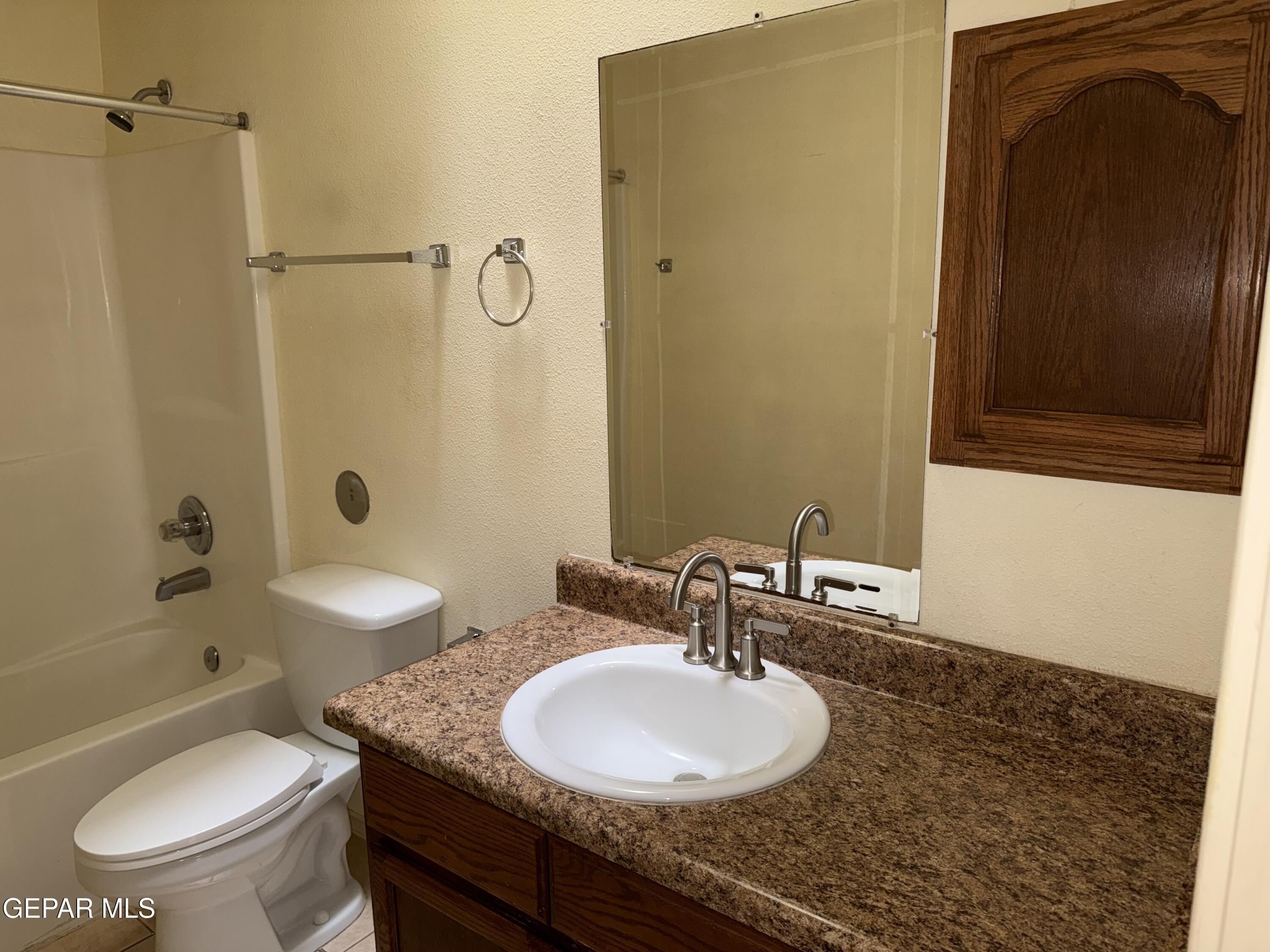 456 Passmore Road Socorro, TX 79927 - Photo 9 of 23 a bathroom with a granite countertop sink toilet a mirror and shower