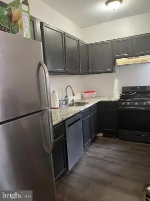 a kitchen with stainless steel appliances a refrigerator a sink and white cabinets