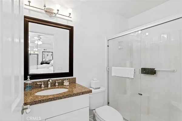 a bathroom with a granite countertop sink toilet a mirror and shower