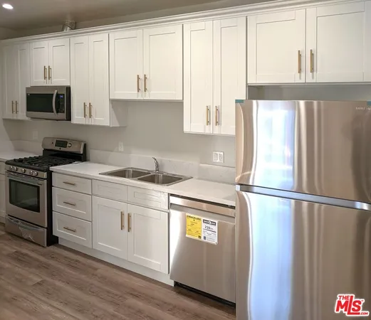a kitchen with stainless steel appliances granite countertop a refrigerator stove and white cabinets