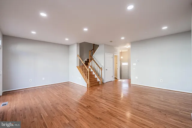 a view of an empty room with wooden floor stairs and a chandelier