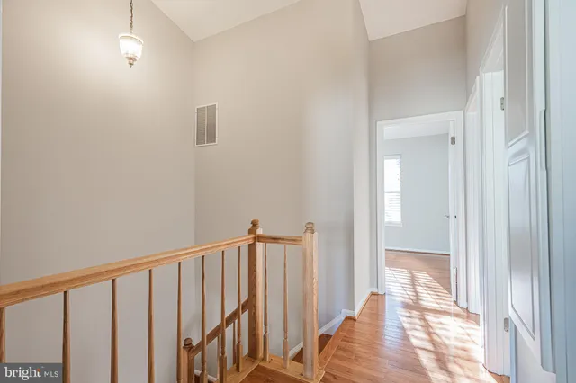 a view of a hallway with wooden floor and a bathroom