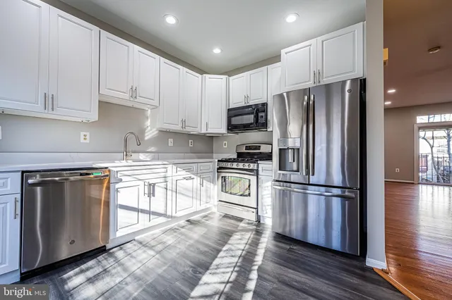 a kitchen with kitchen island granite countertop white cabinets and stainless steel appliances