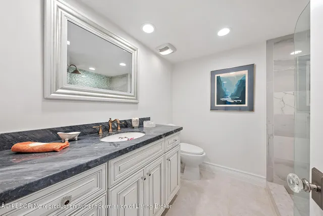 a bathroom with a granite countertop sink mirror and toilet