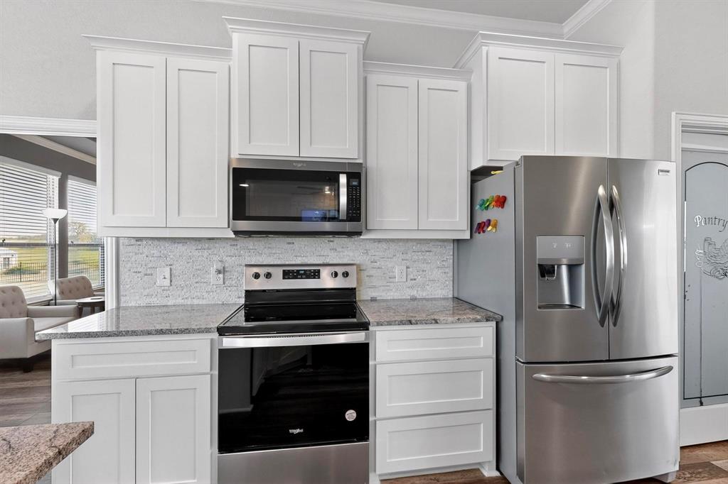 634 Gant Road Sherman, TX 75090 - Photo 14 of 40 Modern kitchen featuring white shaker cabinetry, granite countertops, and a mosaic tile backsplash