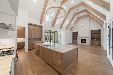 a large white kitchen with a large window a oven and stainless steel appliances
