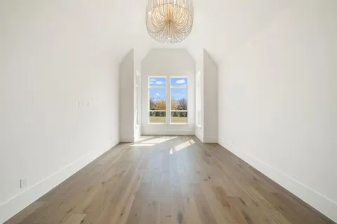 an empty room with wooden floor windows and closet