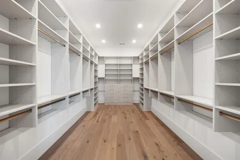 a view of walk in closet with wooden floor and a window